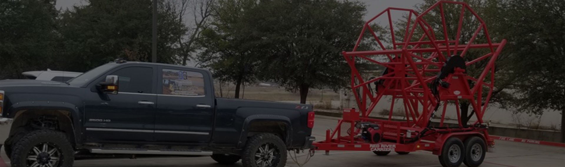 Large blue Chevy Z71 pulling red poly service equipment.