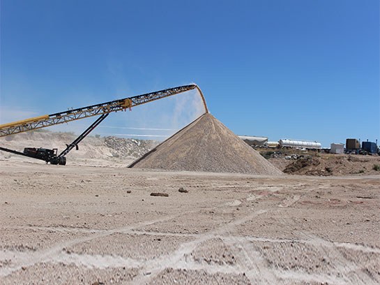 Large crusher service machine with unloading a large pile of dirt.