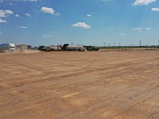 Large dirt field filled with 18 wheelers.
