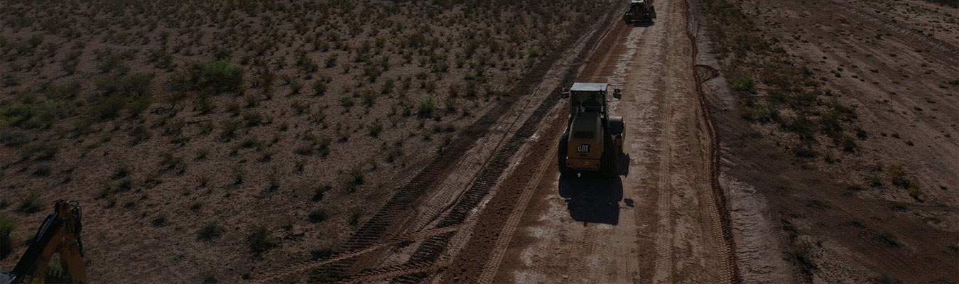 Faded background of an aerial view of heavy machinery drive down a dirt road.