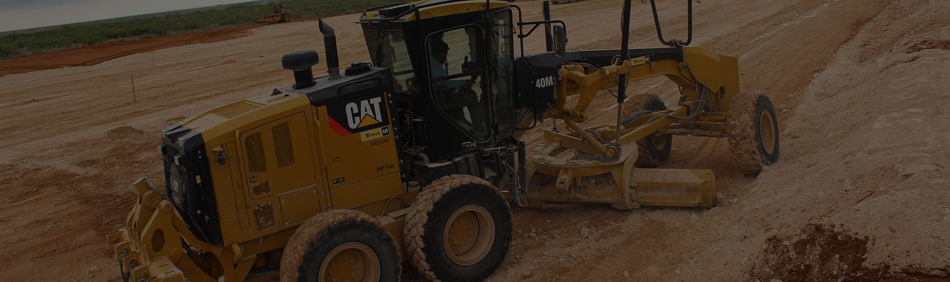 Large yellow caterpillar pulling heavy machinery in a dirt field.